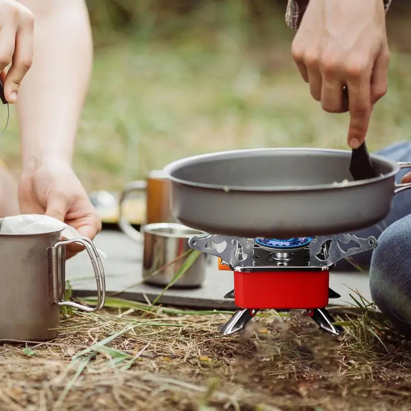 A hiker in Alberta's scenic mountains carefully using a small, lightweight backpacking stove to cook a meal during a break on the trail.