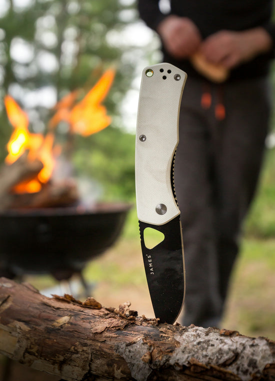 white and black James pocketknife sticking on branch