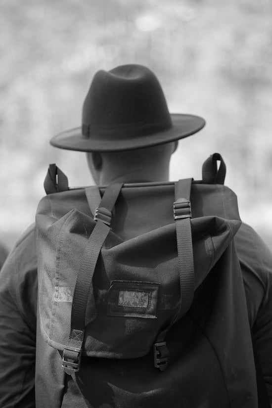 grayscale photo of man wearing hat and backpack
