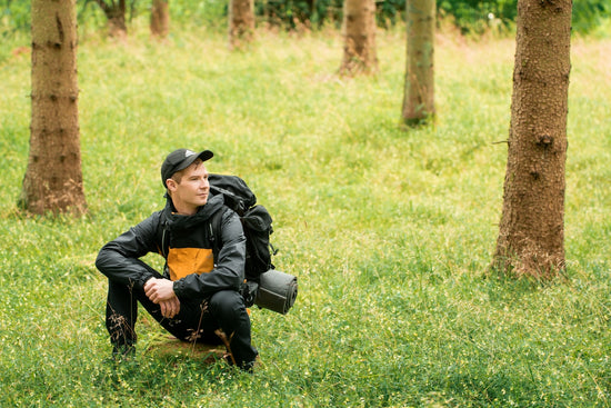 man in black jacket and black pants lying on green grass field during daytime