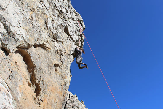 man in black jacket and black pants climbing on rocky mountain during daytime