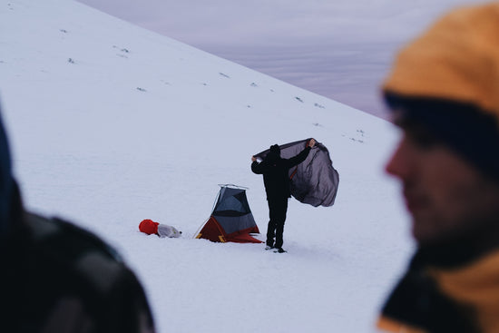 man in black jacket and black pants sitting on snow covered ground during daytime