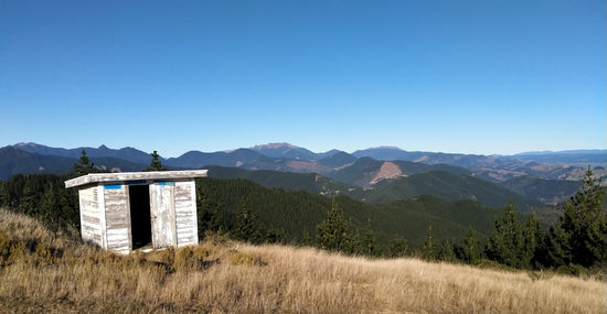 green grass field near mountain under blue sky during daytime