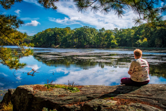 a person sitting on a rock looking at a lake