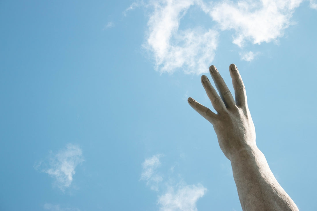 a statue of a hand reaching up into the sky