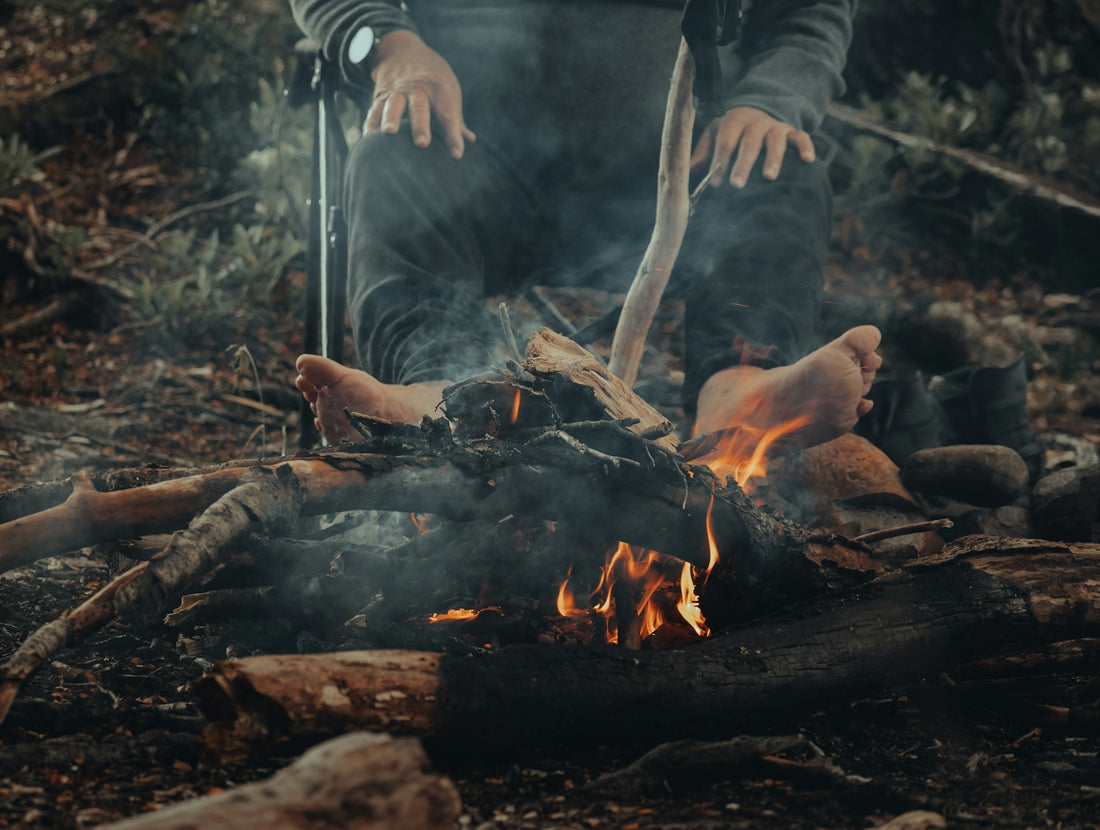 a person standing over a fire in the woods