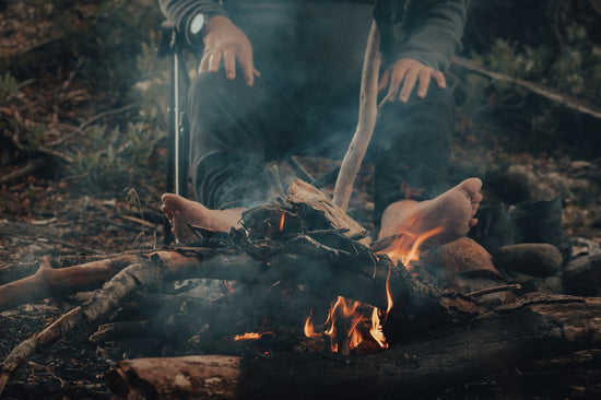 a person sitting in front of a fire in the woods