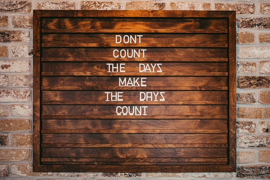 a wooden sign that says don't count the days make the days count