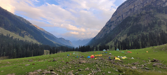 a group of tents in a valley between mountains