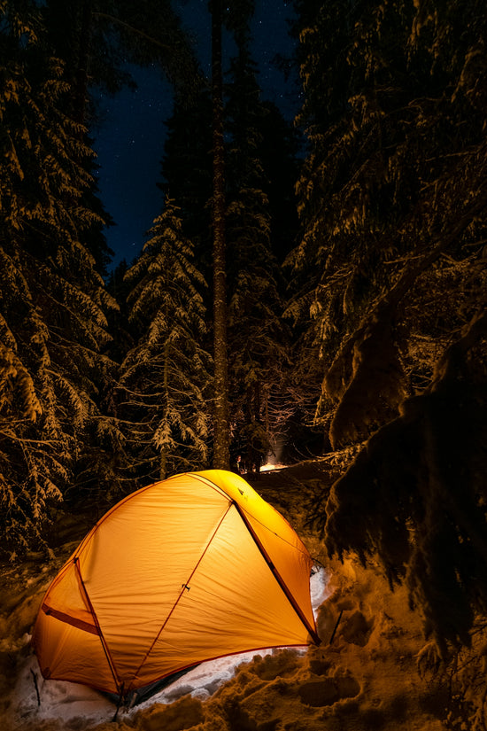 a tent pitched up in the snow at night
