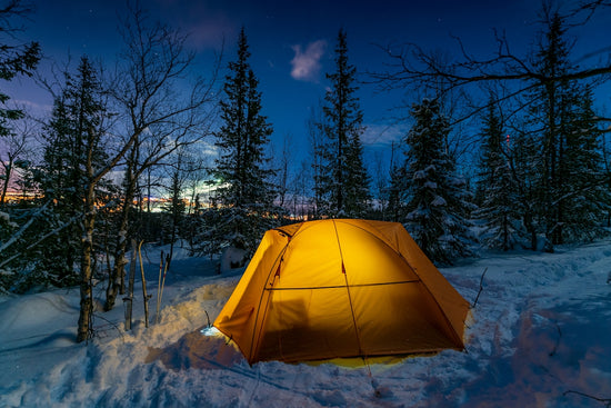 a tent pitched up in the snow at night