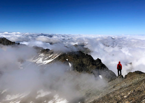 a man standing on top of a mountain above clouds