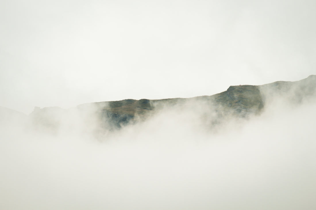 a mountain covered in fog and clouds on a cloudy day