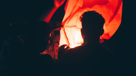a man standing in front of a lit lantern