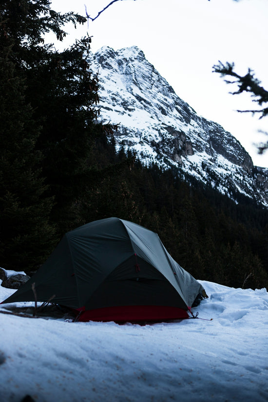 a tent in the snow with a mountain in the background