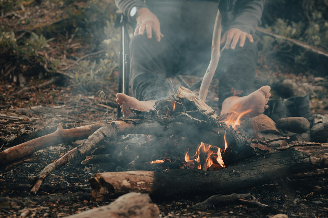A man sitting in front of a fire in the woods