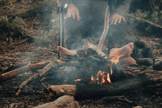 A man sitting in front of a fire in the woods