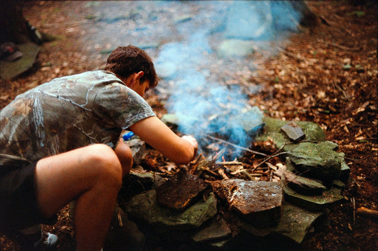 A person sitting next to a fire in the woods