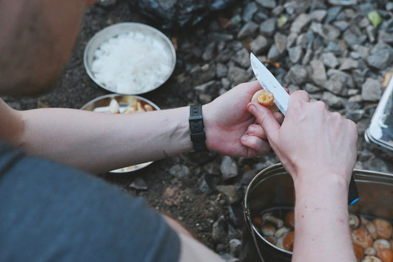 A person holding a knife over a bowl of food