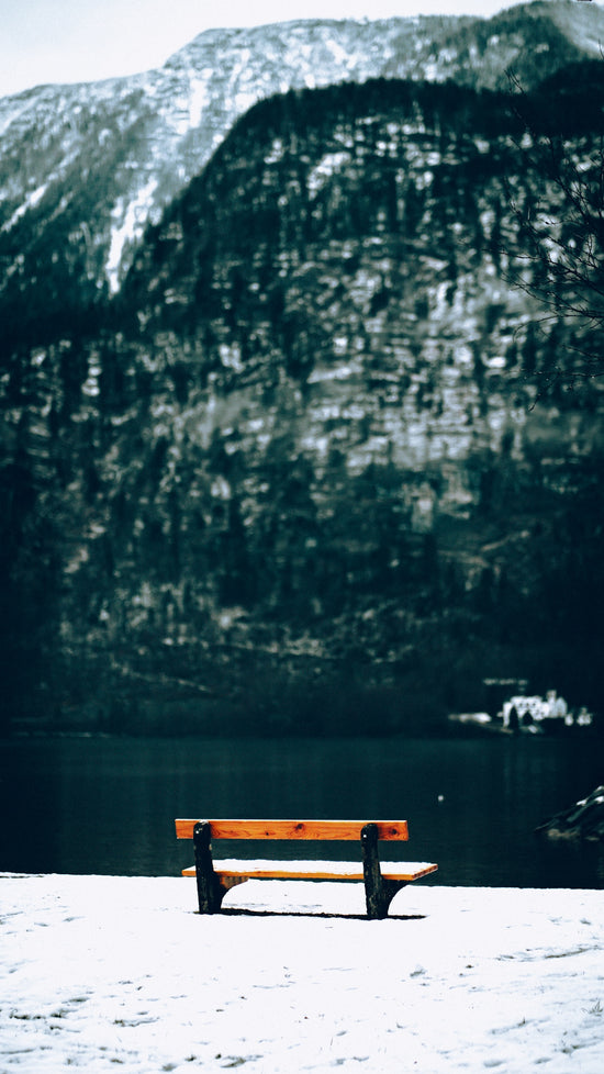 A wooden bench sitting on top of a snow covered ground