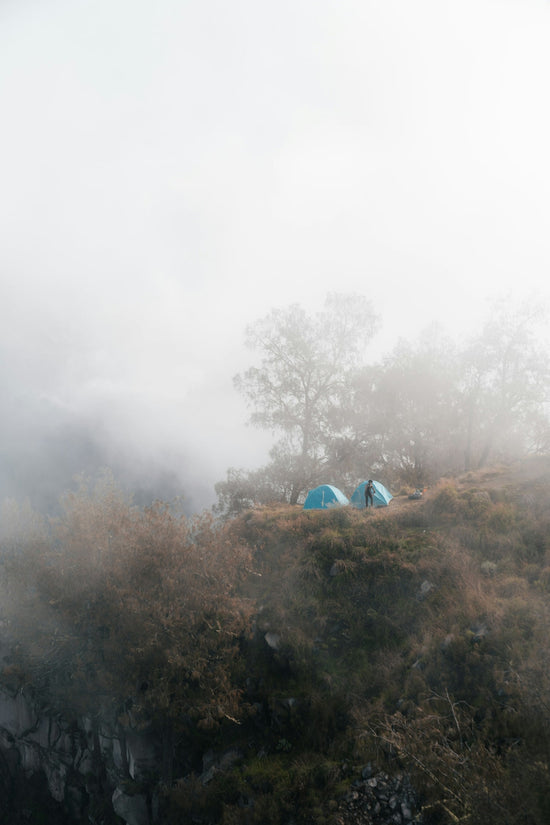 Two tents sit on a foggy mountaintop.