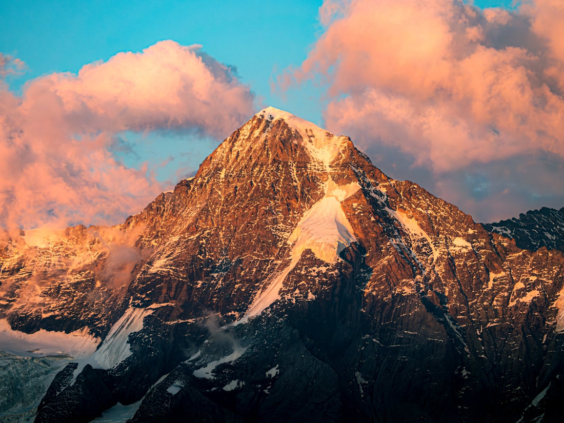 A majestic mountain peaks amongst the clouds.