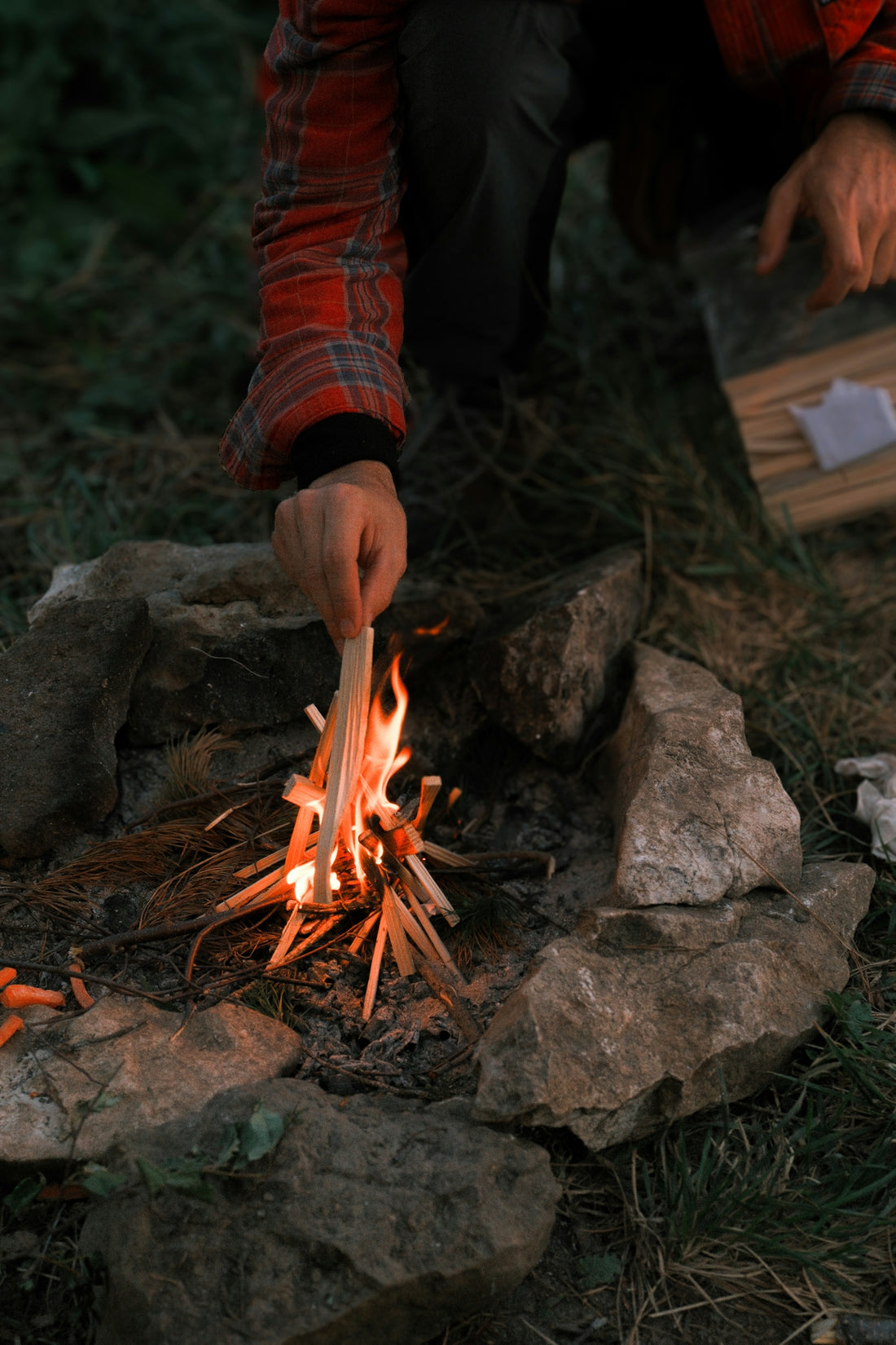 Someone is starting a small campfire outdoors