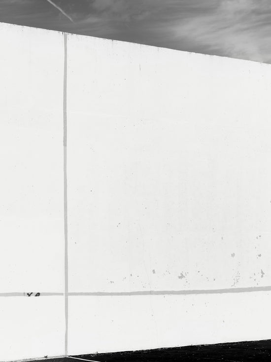 A stark white wall with subtle lines against sky