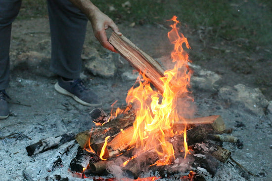 Person adding wood to a campfire
