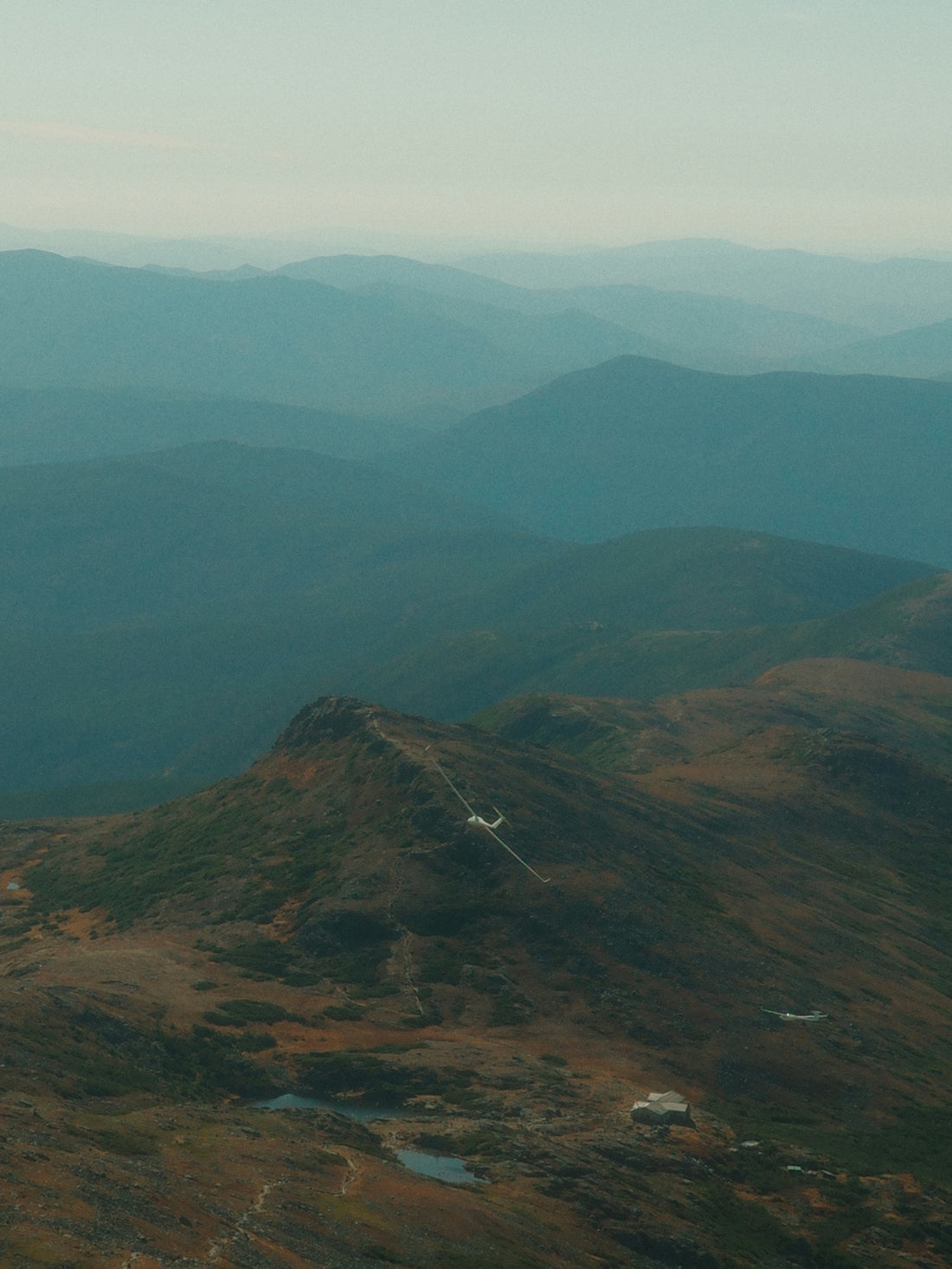 Layered mountain ranges fade into a hazy sky.