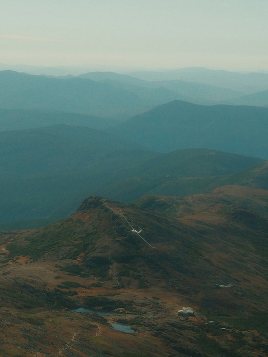 Layered mountain ranges fade into a hazy sky.