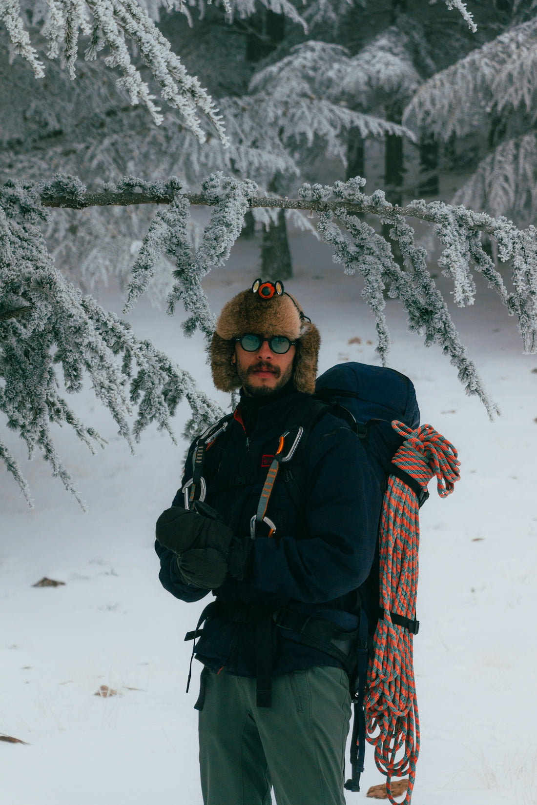 Man in winter gear with backpack and rope.