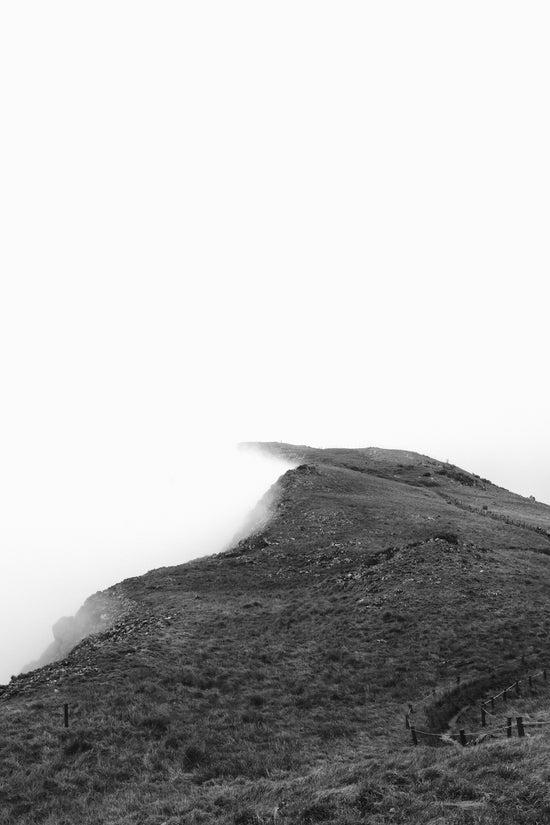 Grassy mountain ridge disappearing into fog