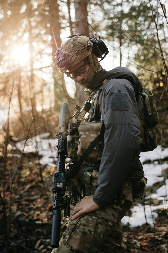 Soldier in camouflage gear with rifle in forest