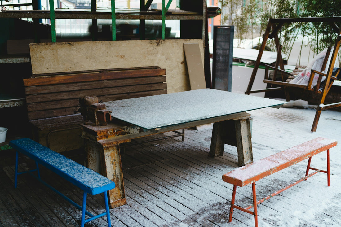 Snow-covered outdoor area with a table, benches, and a swing.