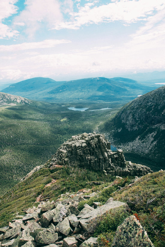 Rocky mountain landscape overlooking a green valley and distant lake