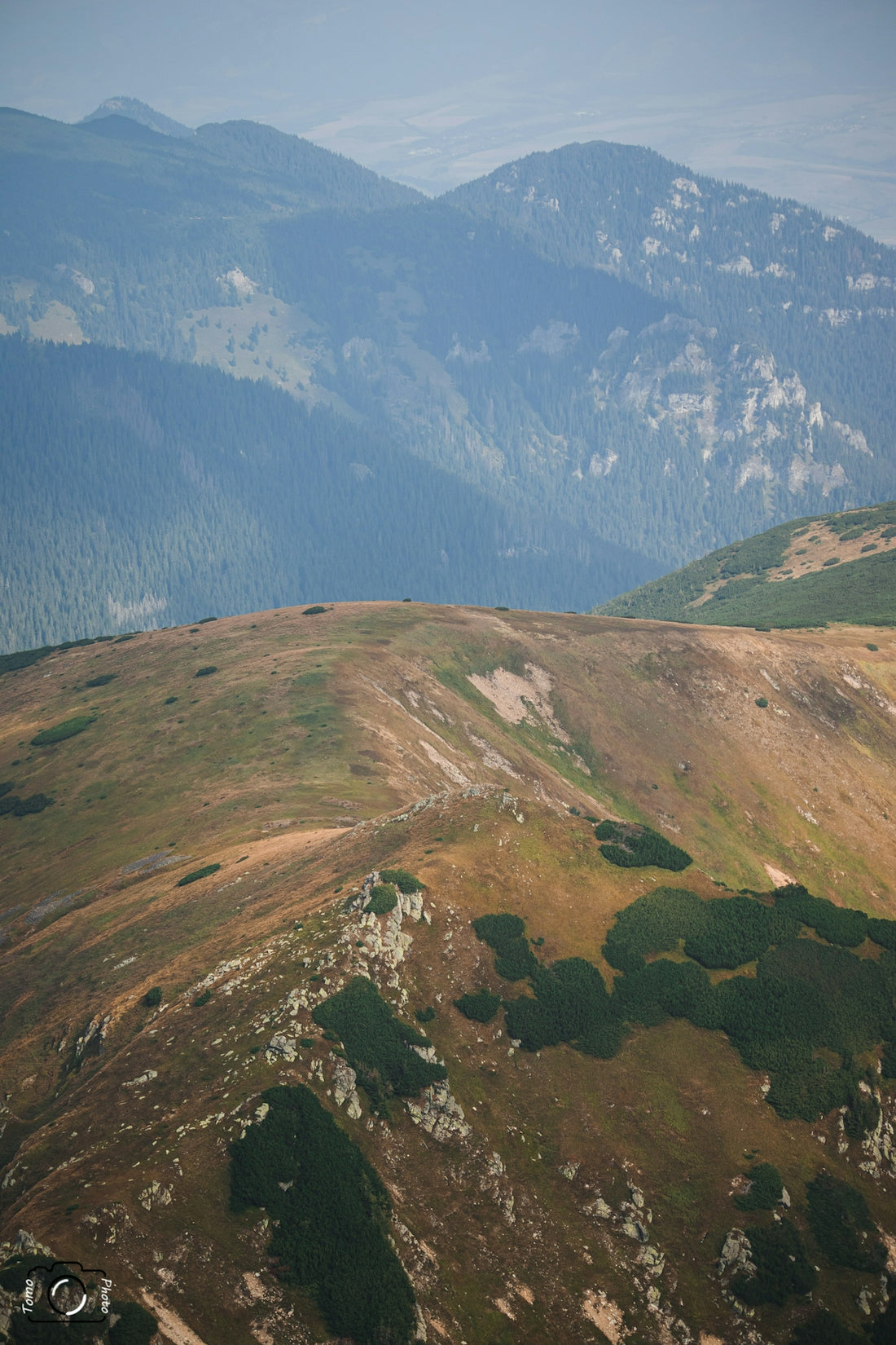Rolling mountain ridges with dry grass and distant hazy peaks.