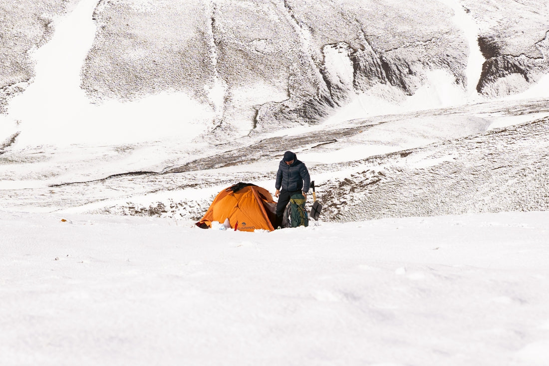 Person camping with a fat bike in snowy mountains.