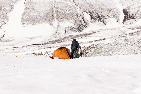 Person camping with a fat bike in snowy mountains.