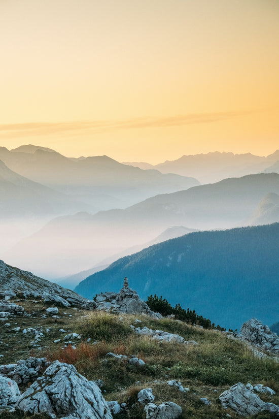 Misty mountain layers under a warm, golden sky.