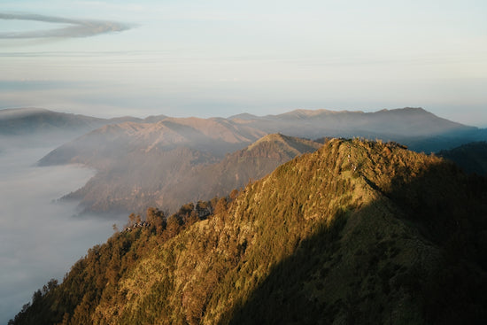 Majestic mountain peaks shrouded in fog during sunrise.