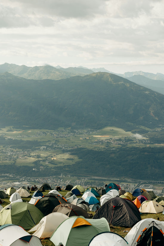 Many tents on a hill overlooking a mountain valley
