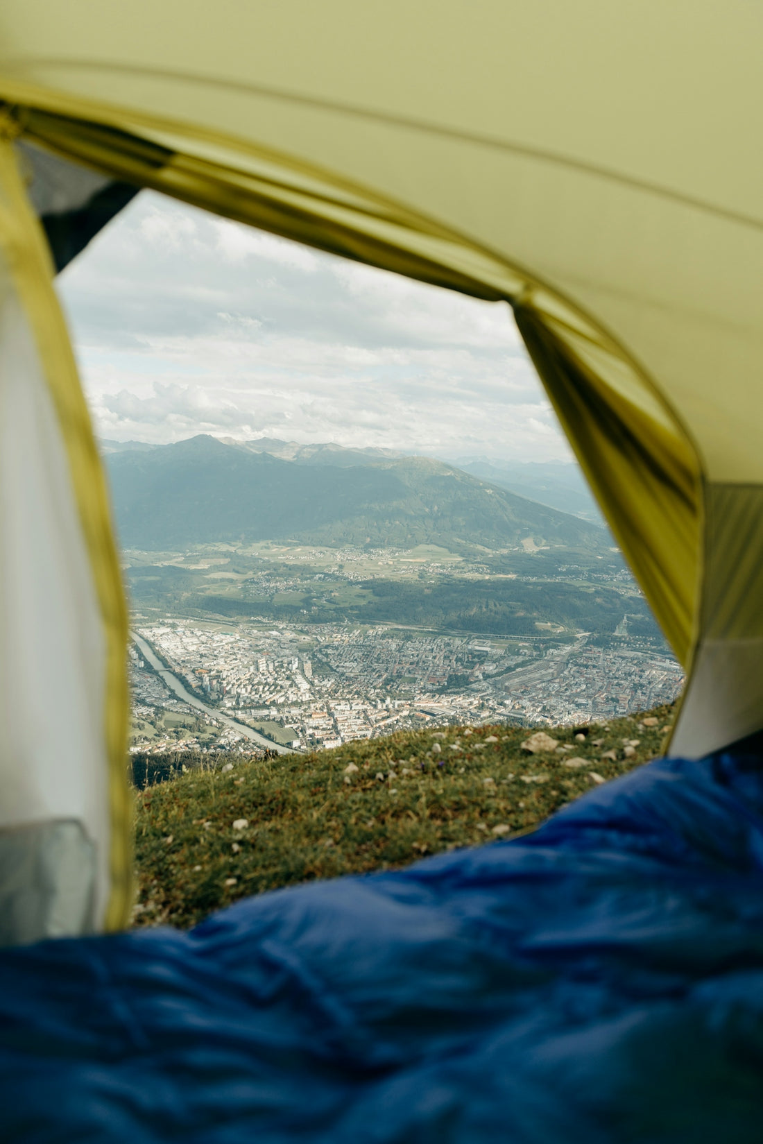 Sleeping bag inside tent with mountain city view.