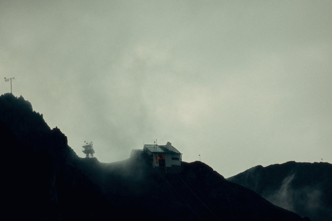 A small building on a dark, foggy mountain slope.