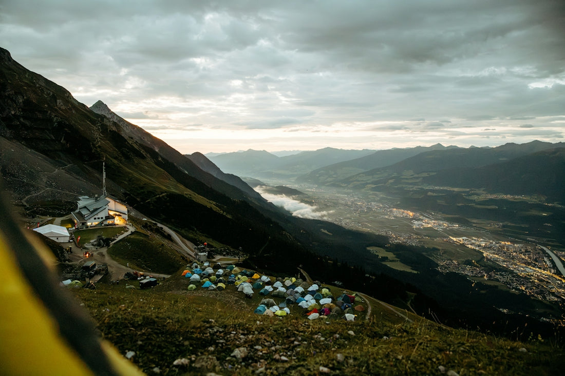 Mountain camp with tents overlooking a vast valley and town