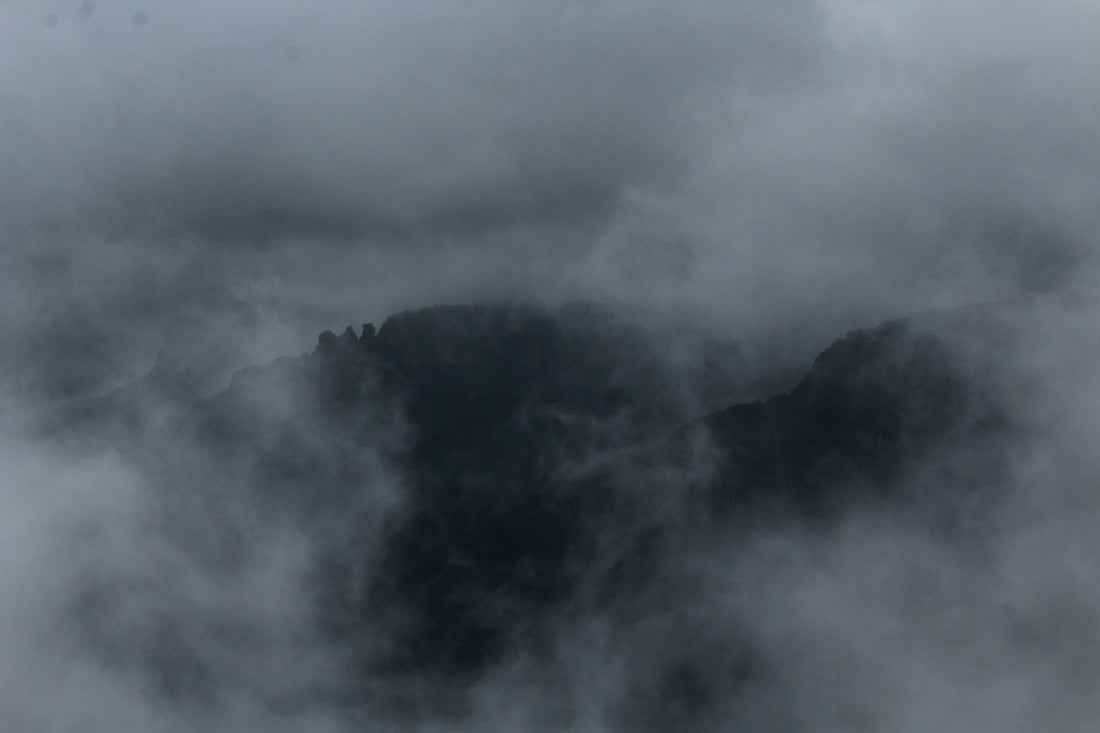 Dark rocky mountain peaks partially obscured by thick grey mist and clouds